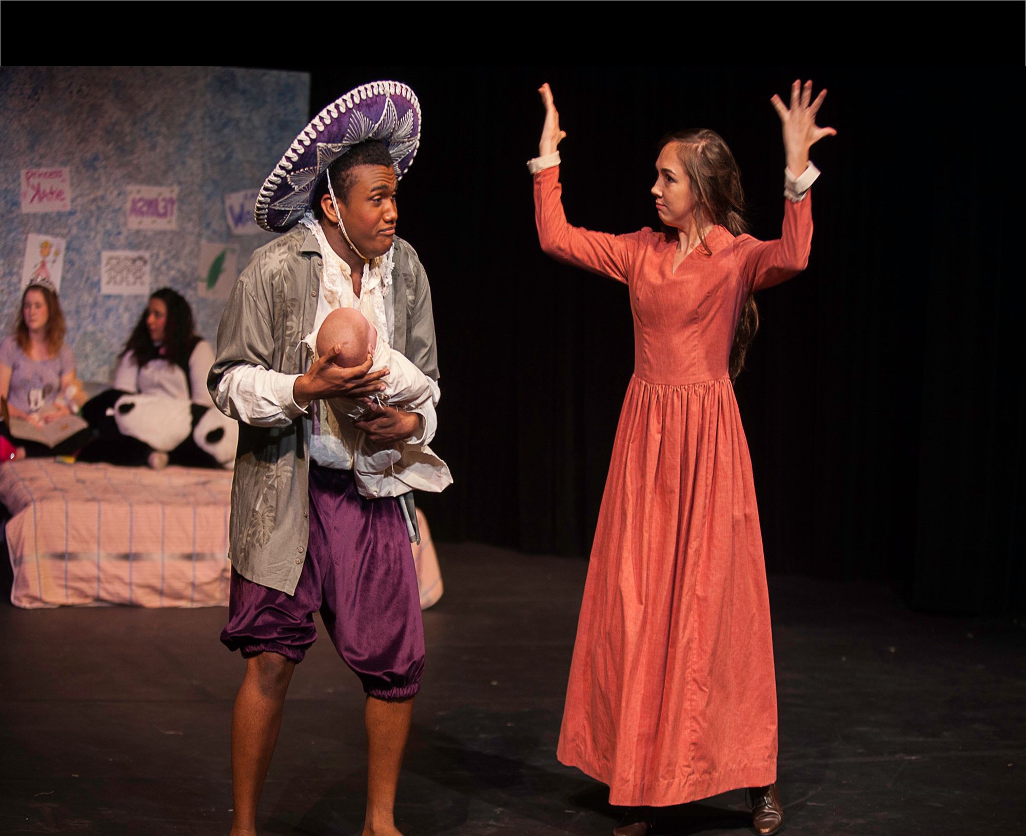 students holding a doll acting on stage