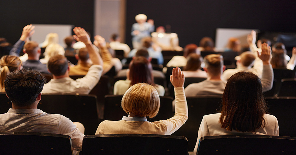 People raising their hand at a lecture 