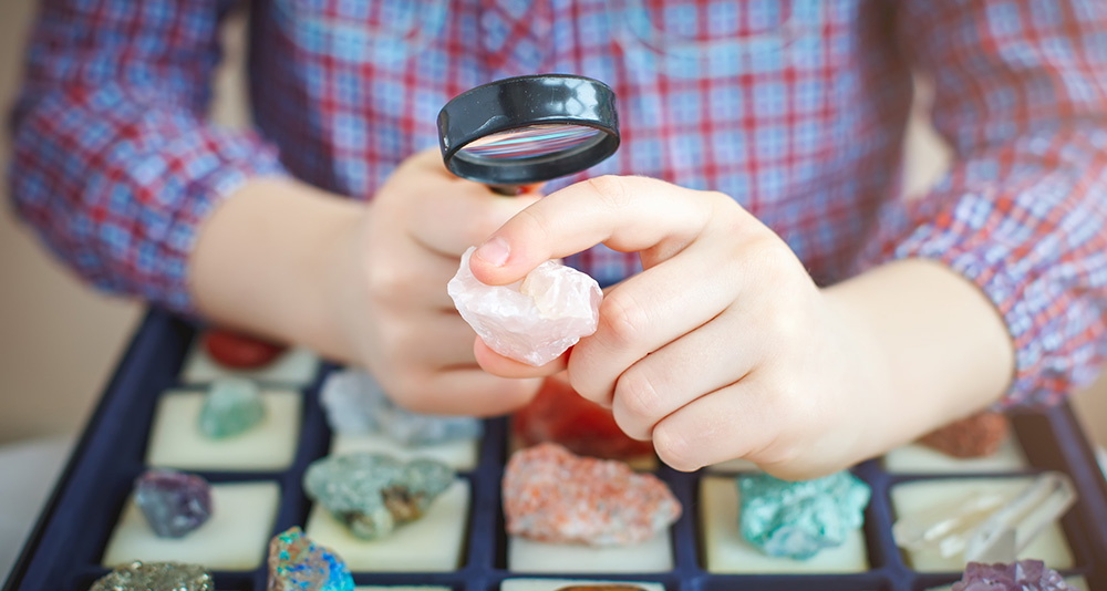 Student examining a stone with a magnifying glass