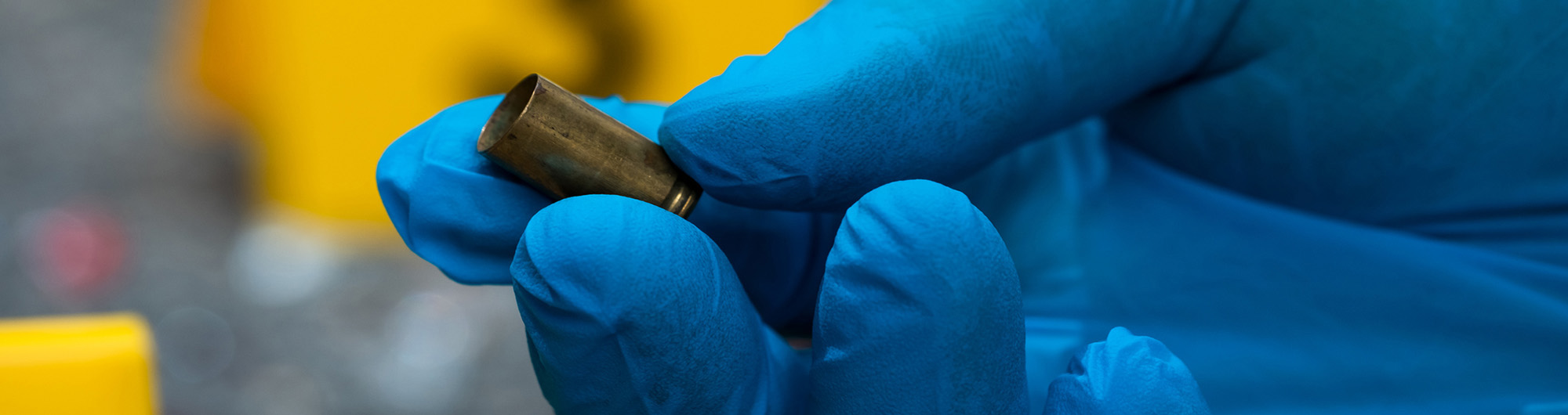 Image of a gloved hand holding a bullet casing 
