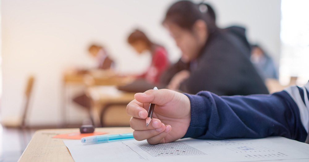 student holding a pencil while taking an exam